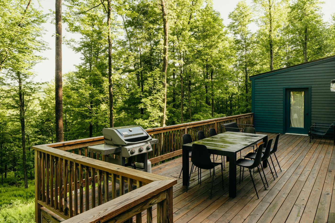 Elevated wood deck with railing overlooking a wooded hillside